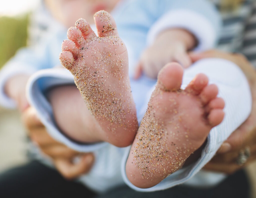 Das Foto zeigt Babyfüße mit Sand
